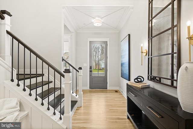 foyer entrance with light wood-style floors, baseboards, ornamental molding, and stairway