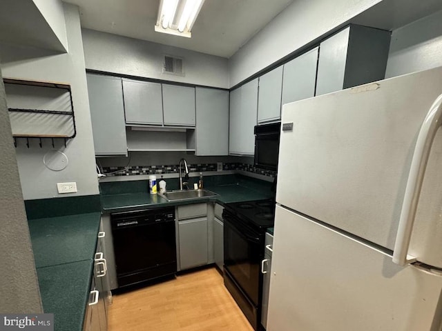 kitchen featuring black appliances, gray cabinetry, light wood-type flooring, and sink