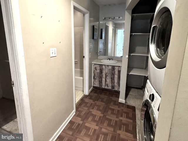 bathroom featuring parquet floors, vanity, and stacked washing maching and dryer