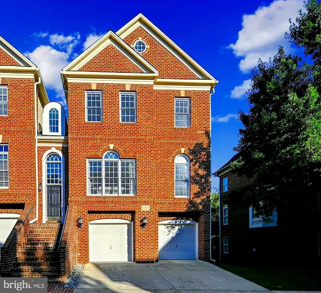 colonial house featuring an attached garage, brick siding, and driveway