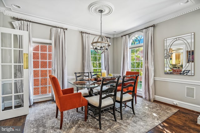 dining space featuring ornamental molding, dark wood-type flooring, and a chandelier