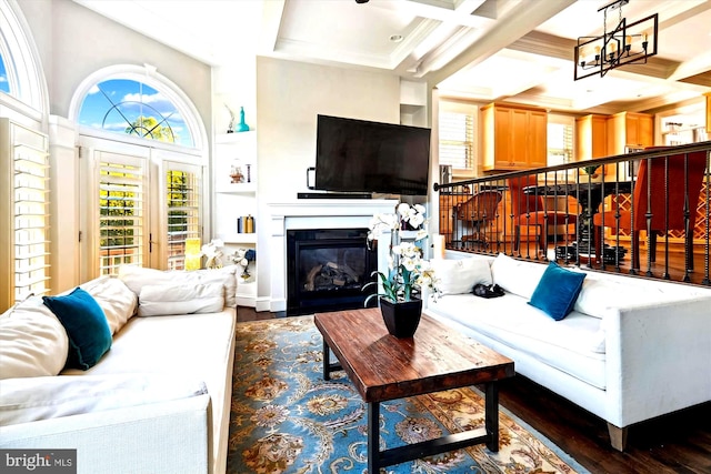 living room featuring beam ceiling, coffered ceiling, an inviting chandelier, crown molding, and dark hardwood / wood-style flooring