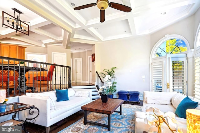 living room with beamed ceiling, ornamental molding, dark wood-type flooring, coffered ceiling, and ceiling fan with notable chandelier