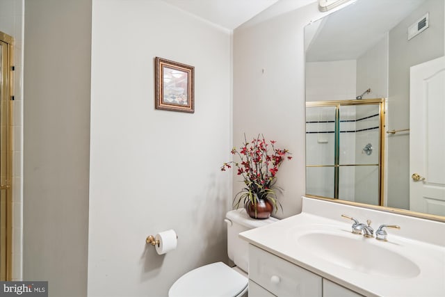 bathroom featuring vanity, toilet, and a shower with shower door