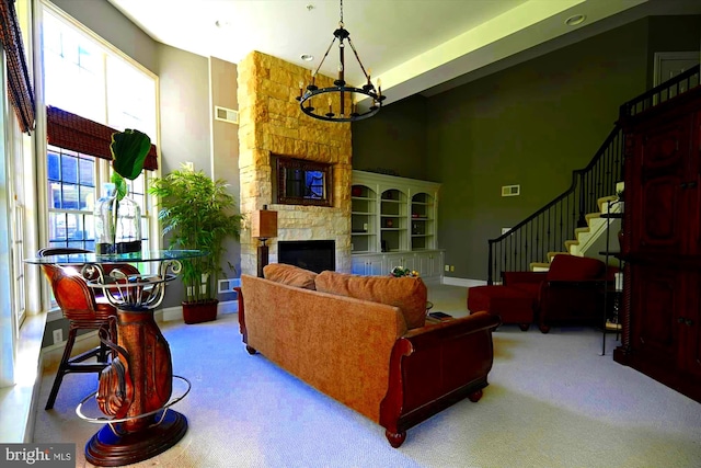 carpeted living room with a fireplace, a notable chandelier, and a towering ceiling