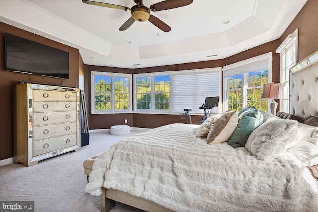 carpeted bedroom featuring ceiling fan and a raised ceiling