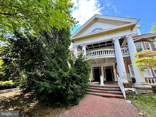 neoclassical home featuring a balcony