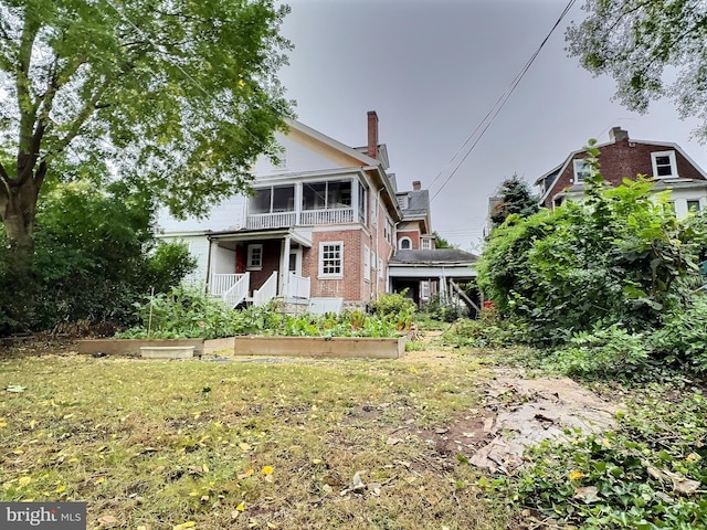 view of front of home featuring a sunroom and a front lawn