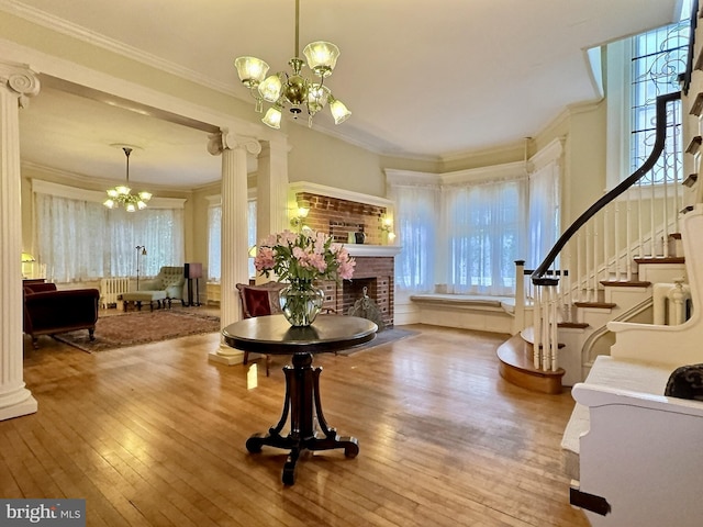 foyer featuring a notable chandelier, crown molding, hardwood / wood-style floors, and a brick fireplace