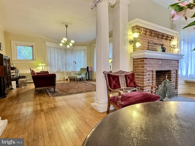 interior space with a brick fireplace, a chandelier, hardwood / wood-style floors, and crown molding