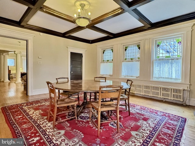 dining room featuring radiator, hardwood / wood-style floors, coffered ceiling, an inviting chandelier, and ornate columns