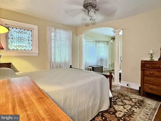 bedroom with hardwood / wood-style floors, decorative columns, multiple windows, and ceiling fan