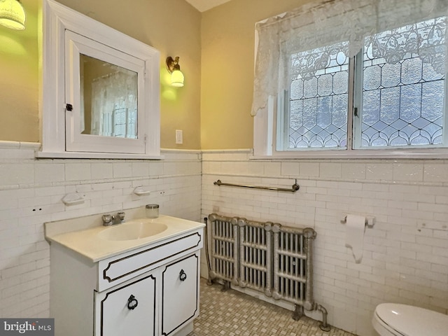 bathroom with vanity, radiator heating unit, tile patterned floors, tile walls, and toilet