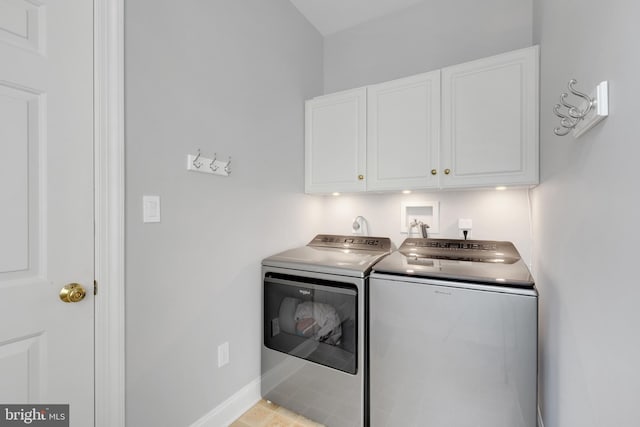 laundry room featuring separate washer and dryer and cabinets