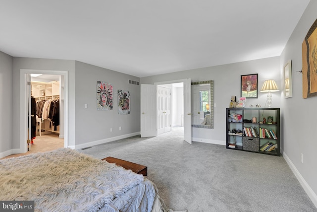 bedroom featuring a spacious closet, a closet, and light colored carpet