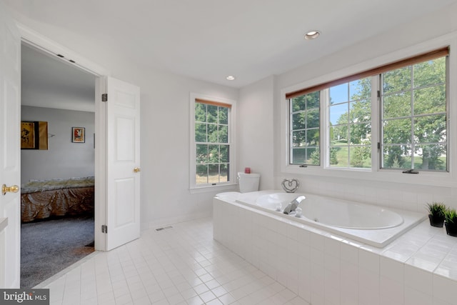 bathroom with a relaxing tiled tub, plenty of natural light, and tile patterned floors