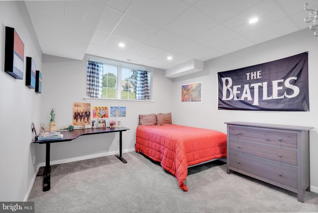 bedroom with light carpet and a paneled ceiling