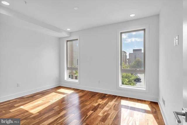 unfurnished room with a healthy amount of sunlight and hardwood / wood-style floors