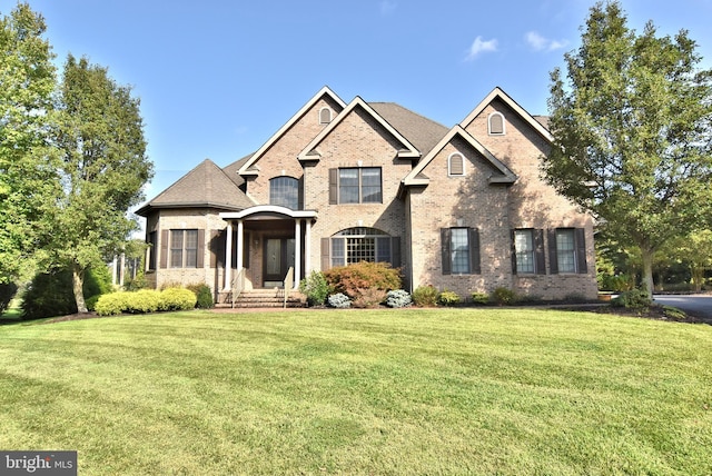 french country style house featuring a front yard and brick siding