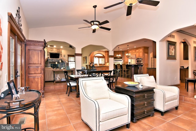 tiled living room with ceiling fan and high vaulted ceiling