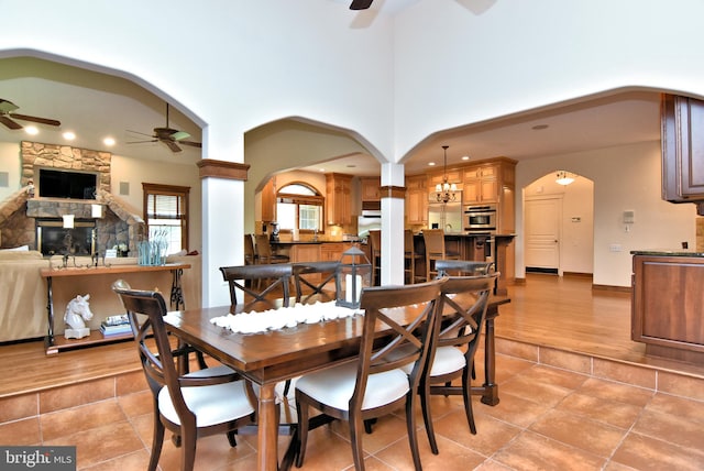 dining space featuring ceiling fan, a stone fireplace, and light hardwood / wood-style floors