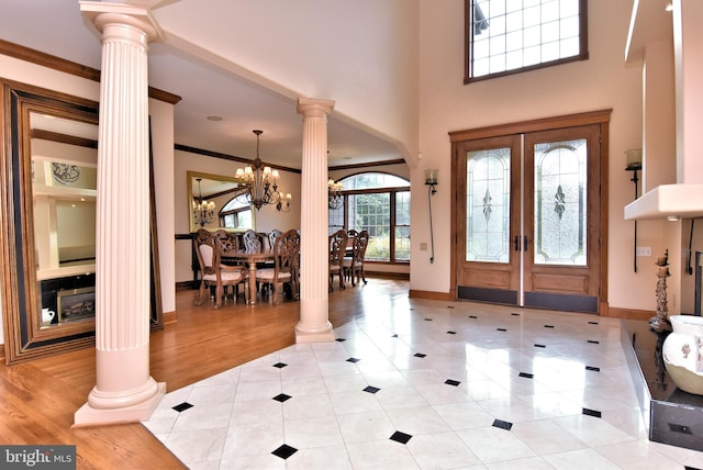 foyer featuring light hardwood / wood-style floors, decorative columns, an inviting chandelier, and french doors