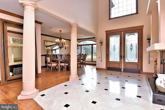 foyer entrance with crown molding, baseboards, decorative columns, an inviting chandelier, and light tile patterned floors