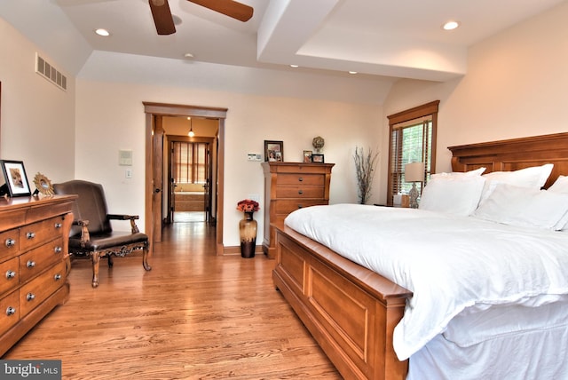 bedroom featuring light wood-style flooring, visible vents, recessed lighting, a ceiling fan, and a raised ceiling
