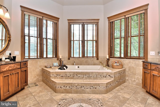 bathroom with tile walls, a wealth of natural light, a garden tub, and vanity