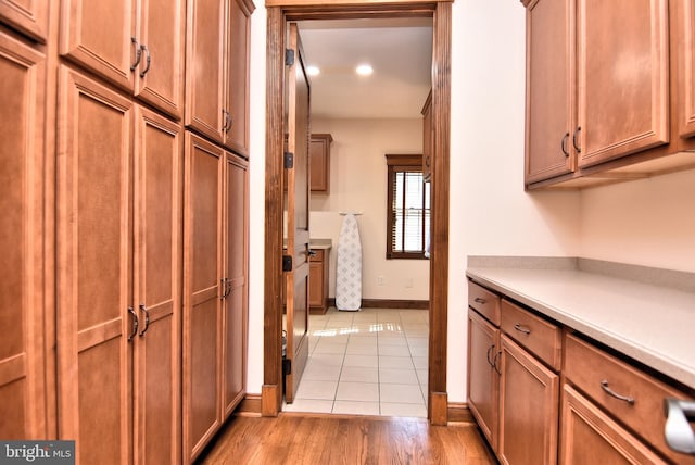 kitchen with light countertops, recessed lighting, baseboards, light wood-style flooring, and brown cabinets