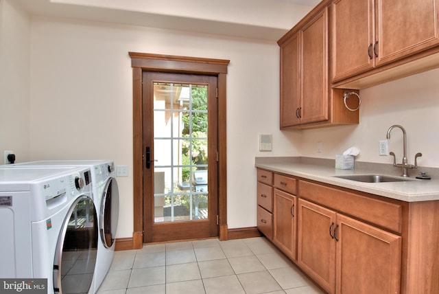 laundry area with a sink, light tile patterned floors, baseboards, washer and dryer, and cabinet space