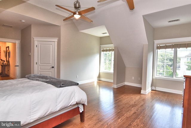 bedroom featuring baseboards, visible vents, wood finished floors, and lofted ceiling