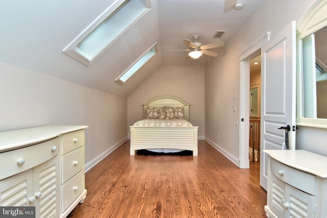 bedroom featuring visible vents, baseboards, vaulted ceiling with skylight, a ceiling fan, and light wood-style floors