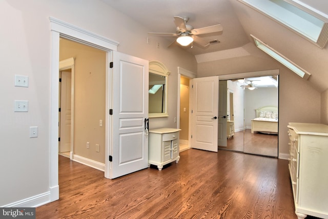 unfurnished bedroom featuring vaulted ceiling with skylight, baseboards, visible vents, ceiling fan, and dark wood-type flooring