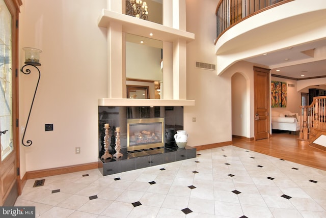 interior space featuring a high ceiling, a tiled fireplace, and hardwood / wood-style flooring