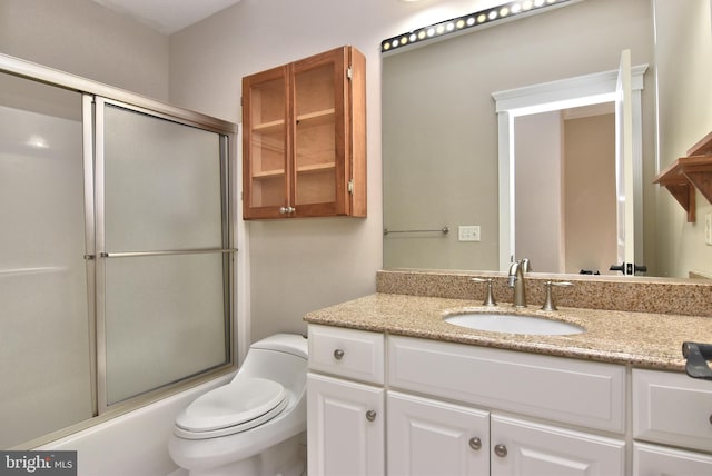 full bathroom with bath / shower combo with glass door, vanity, and toilet