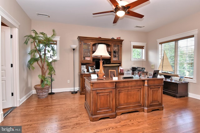 office space featuring visible vents, light wood-style floors, and a ceiling fan