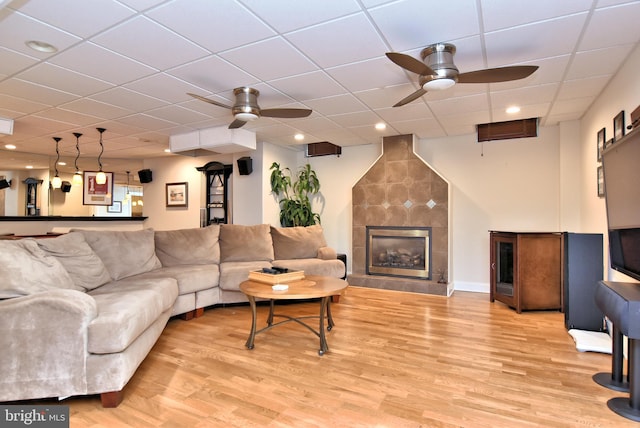 living room featuring ceiling fan, a paneled ceiling, light hardwood / wood-style floors, and a large fireplace