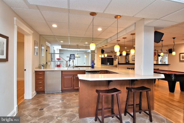 kitchen with light countertops, a peninsula, a breakfast bar area, and pendant lighting