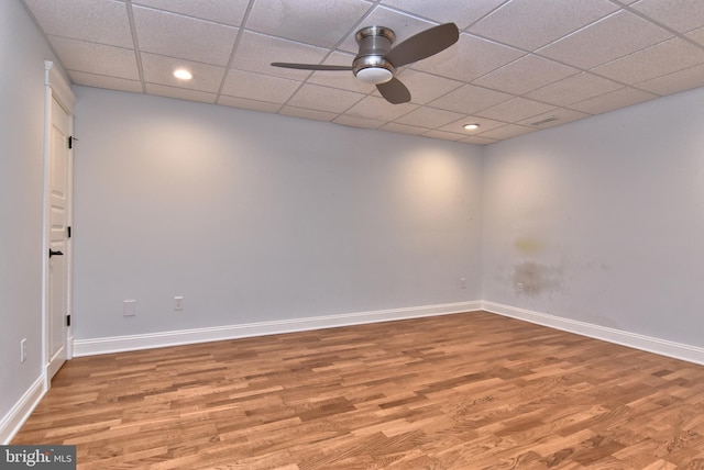 empty room with baseboards, wood finished floors, ceiling fan, and a paneled ceiling