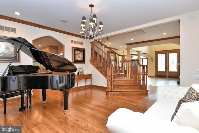 interior space featuring crown molding, stairs, an inviting chandelier, visible vents, and wood finished floors