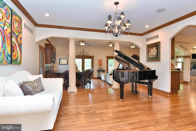 living room featuring ceiling fan with notable chandelier, crown molding, light hardwood / wood-style flooring, and ornate columns