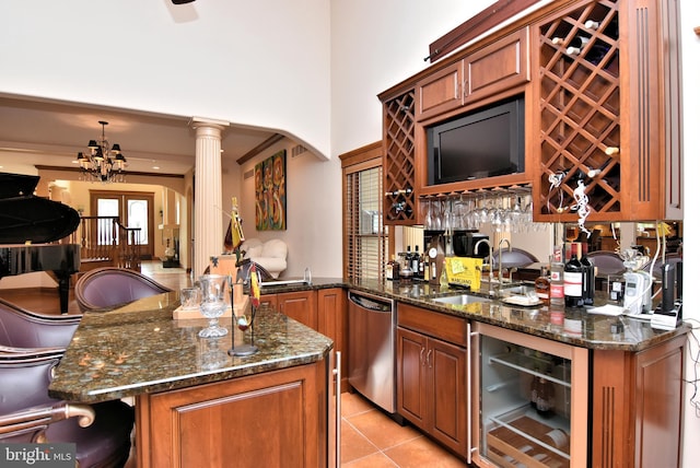 kitchen with kitchen peninsula, stainless steel dishwasher, beverage cooler, decorative columns, and an inviting chandelier