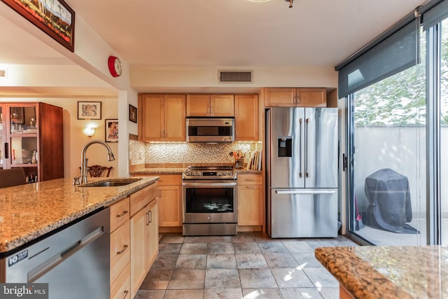 kitchen with sink, stainless steel appliances, backsplash, light tile patterned floors, and light stone countertops