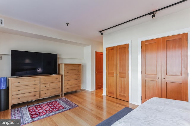 bedroom featuring light hardwood / wood-style floors and multiple closets