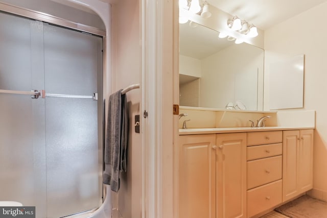 bathroom featuring a shower with door and vanity