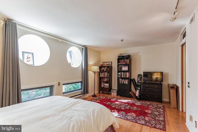 bedroom with hardwood / wood-style flooring and track lighting