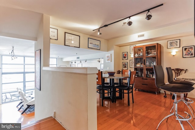 dining room with wood-type flooring and track lighting