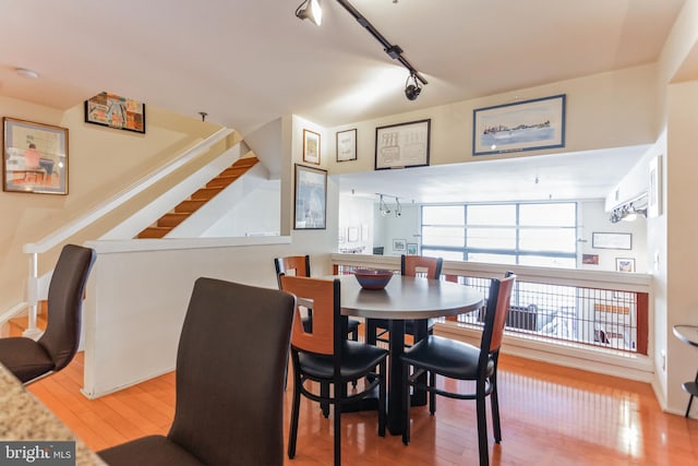 dining area with wood-type flooring and rail lighting