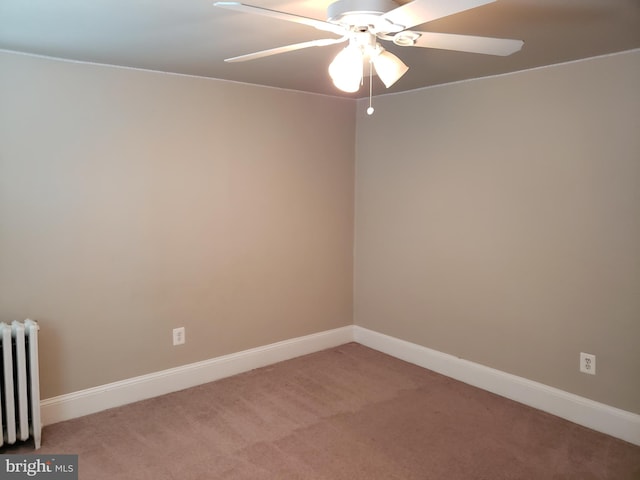 spare room featuring radiator, ceiling fan, and light colored carpet